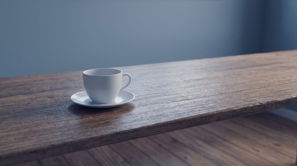A white cup and saucer on a long bare wooden desk.