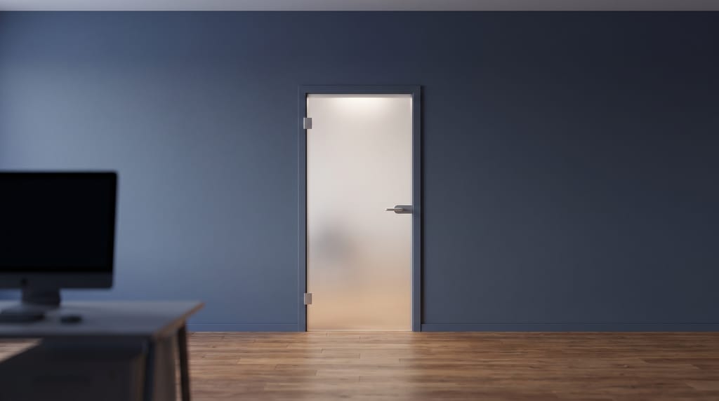 A closed frosted-glass door in a navy wall, soft light behind the glass.