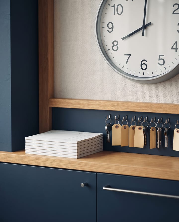 A rental counter at opening: a stack of forms, bicycle keys on hooks with blank tags, and a large wall clock at eight.